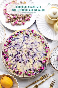 a white chocolate cake with pink and purple swirled icing on it, surrounded by other desserts