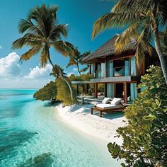 a beach house on an island with palm trees in the foreground and clear blue water