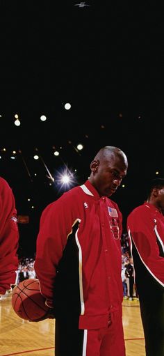 three men in red uniforms standing on a basketball court