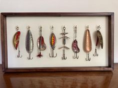 a shadow box with different types of fishing lures in it on a wooden table