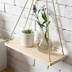 two vases with plants are hanging on a shelf next to a brick wall,