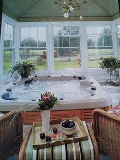 a large hot tub sitting in the middle of a room next to two wicker chairs