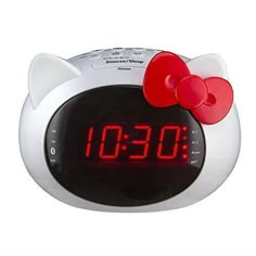 an alarm clock with a hello kitty face on it's face and red bow