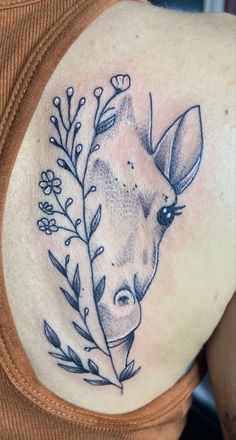 a woman's shoulder with a tattoo of a giraffe and flowers on it