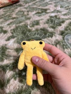 a hand holding a small yellow stuffed animal