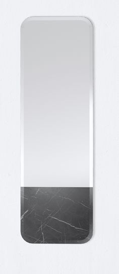 a square mirror with a black and white marble pattern on the bottom, against a white wall