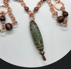 Tibet Agate "heaven's eye" Necklace Bronze and Wood Beads in Copper 40" long Main focal is approximately 2 1/4" long Dzi (pronounced Zee) is a Tibetan word used to describe a patterned, usually agate, of mainly oblong, round, cylindrical or tabular shape pierced lengthwise called Heaven's Bead (tian zhu) in Chinese. This bead has 3 "eyes" - The 3 eyed Dzi bead represents the three stars of luck, happiness, honor, and longevity. It is the bead of wealth and health to bring continuous fortune. Coa Beaded Agate Amulet Necklaces, Tibetan Beads Jewelry, Brown Amulet Necklace With 108 Beads, Tibetan Necklace Bohemian, Tibetan Necklace, Tibetan Jewelry, 3rd Eye, Three Star, Eye Necklace