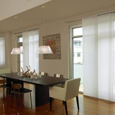 the dining room table is surrounded by chairs and lights, along with two lamps hanging from the ceiling