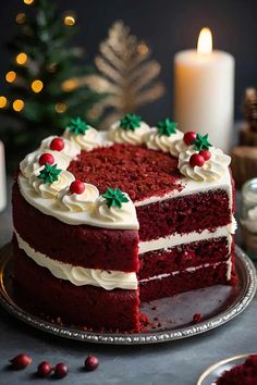 a red velvet cake with white frosting on a plate next to a lit candle