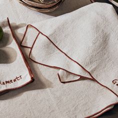 two towels with embroidered names on them sitting next to an apple and bowl of fruit