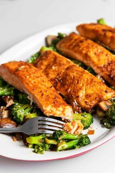 salmon and broccoli on a white plate with a fork next to the dish