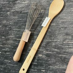 a wooden spoon and whisk are sitting on the table next to each other