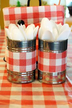 two glass jars with white flowers in them on a red and white checkered table cloth