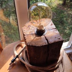 a light bulb sitting on top of a piece of wood next to a glass window