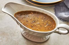 a white gravy in a bowl on top of a table next to plates