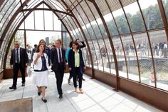 some people are walking around in a glass building and one is holding her hand up