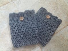 two gray crocheted mittens sitting on top of a tile floor next to each other