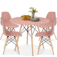 a pink table with four chairs around it and a bowl of fruit on the table