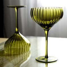 two green wine glasses sitting on top of a table