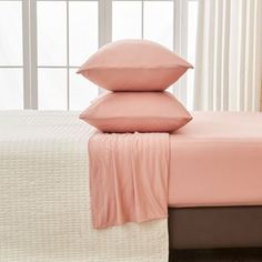 a bed with pink sheets and pillows on it