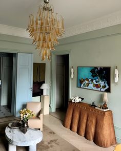 a living room filled with furniture and a chandelier hanging over the top of it