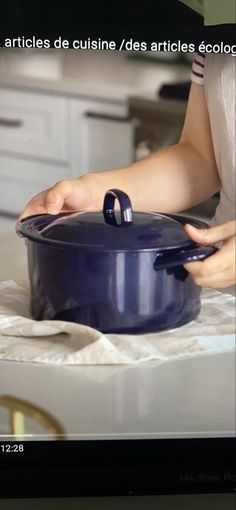 a woman is cooking in a blue pot on the stove top, with her hands resting on the lid