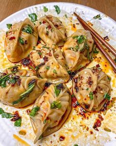 some dumplings are on a plate with chopsticks