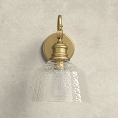 a bathroom light that is on the wall with a glass shade over it's head