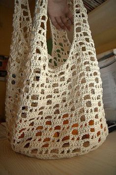 a crocheted bag sitting on top of a table next to a person's hand