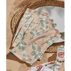 three napkins and two hats on top of a straw hat with an orange flower print