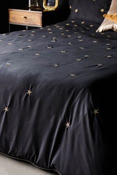 a black bedspread with gold stars on it and two nightstands in the background