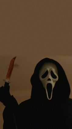 a person wearing a ghost mask holding a knife in one hand and a scream face on the other