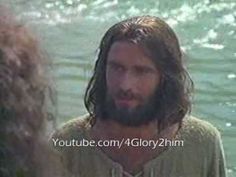 a man with long hair and beard standing next to another person in front of water