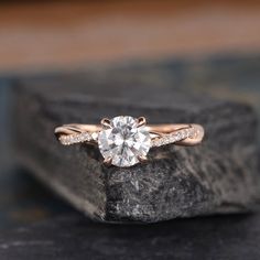 an engagement ring on top of a rock with a diamond in the center and side stones around it