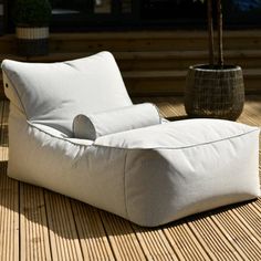 a white chair sitting on top of a wooden floor next to a potted plant