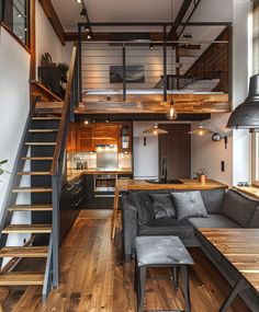 a living room filled with furniture next to a kitchen and loft style staircase leading up to the second floor