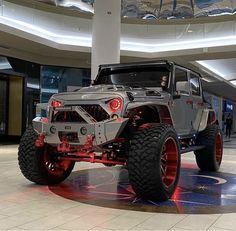 a jeep is on display in the lobby of a shopping mall, with its lights on