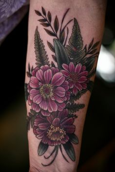 a woman's arm with flowers and leaves on it