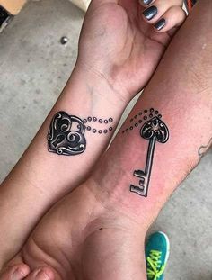 two people with matching tattoos on their arms, both holding each other's hands