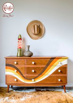 a hat is sitting on top of a dresser in a room with a cowhide rug