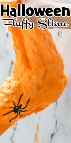 an orange slime with black spider on it and the words halloween fluffy slime