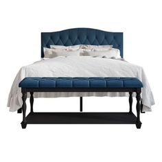 a bed with a blue upholstered headboard and white linens on it