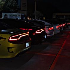 a row of cars parked next to each other in a parking lot at night time