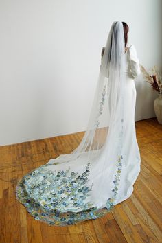 a woman in a wedding dress with a veil on her head and flowers on the floor