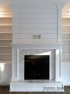 a white fireplace with built in bookcases behind it