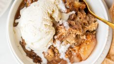 a white bowl filled with ice cream and apple crisper cobbler next to crackers