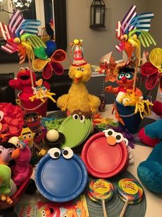 sesame street party supplies including plates, cups and spoons on a dining room table