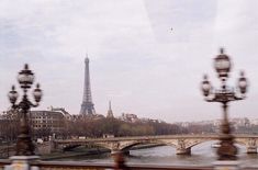 the eiffel tower is seen from across the river, with street lamps on either side