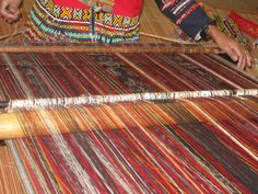 a woman is weaving fabric on a loom