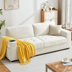 a living room with a white couch and yellow throw blanket on the back of it